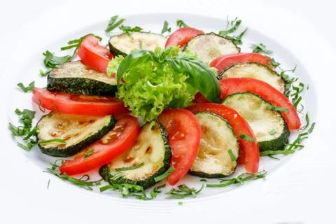 Fried vegetable marrows with greenery and tomatoes. Stock Photos