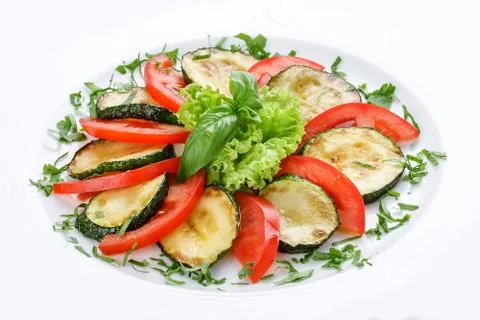 Fried vegetable marrows with greenery and tomatoes. Stock Photos