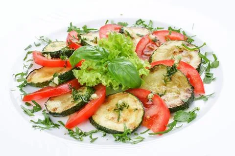 Fried vegetable marrows with greenery and tomatoes. Stock Photos