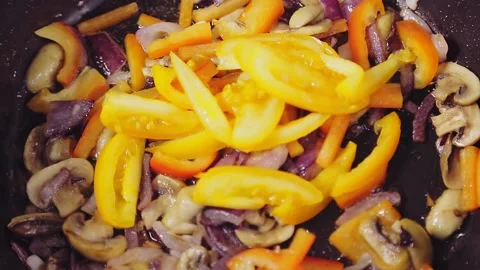 Fried vegetables in a pan adds tomatoes orange female hand Stock Footage 149003957