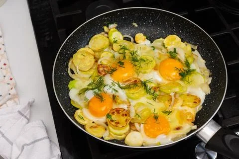 Fried zucchini is cooked with scrambled eggs in a pan on a stovetop. The sc.. Stock Photos