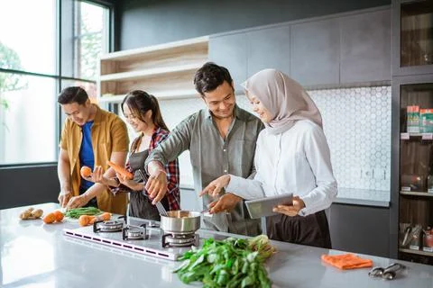 Friend cooking together in the kitchen while looking at online course from 스톡 사진