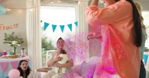 Friend gesturing to reveal prop, guiding mother-to-be, pink confetti bursting, Stock Footage 330756604