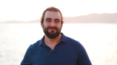 Friendly bearded man turns to camera, say hello and starts laughing 스톡 동영상 160149379