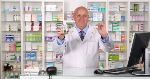 Friendly Chemist Offering Pills Treatment and a Glass of Water in a Drugstore Stock Footage 83673541