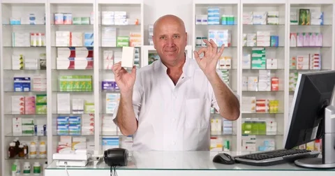 Friendly Chemist Presenting Best Vitamins with Ok Hand Gesture in a Drugstore Stock Footage 75743801