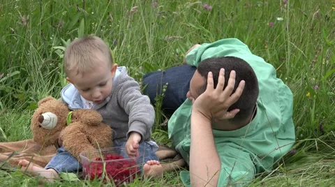 Friendly child with teddy bear toy feeding father in nature  Video stock 46208510
