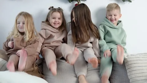 Friendly children sit on the back of the sofa and play near the Christmas and Stock Footage 145748223