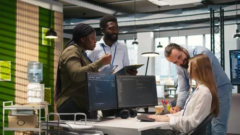 Friendly coworkers helping junior dev code AI algorithms to debug software 스톡 사진