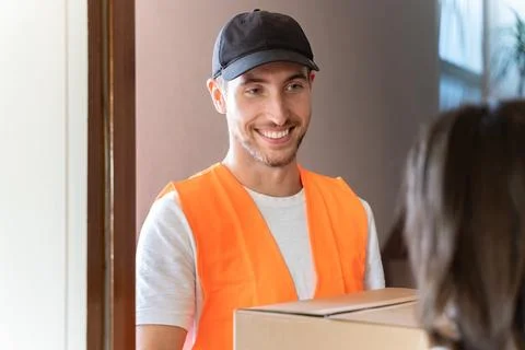 Friendly delivery man delivers package to customer at home Foto stock