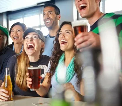 Friendly drinks and sports action go hand in hand. A group of friends cheering Stock Photos