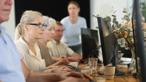 Friendly elderly computer course teacher helping senior woman learn computer Stock Footage 310068877