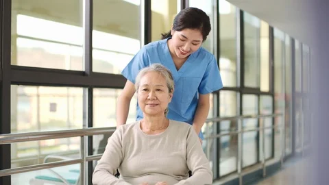 Friendly employee of nursing home talking to senior asian woman Stock Footage