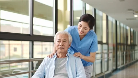 Friendly employee of nursing home talking to wheelchair bound senior man Stock Footage 123053877