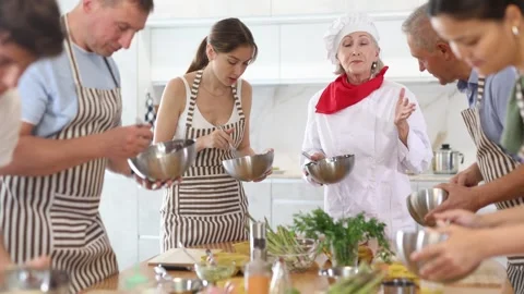 Friendly experienced senior female chef giving culinary classes to group of men Stock-Footage 341426442