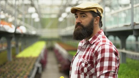 Friendly farmer smiling at camera and showing greenhouse, successful business Vidéo 118915329