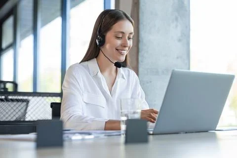 Friendly female helpline operator in call center. Young woman working in call Stock Photos