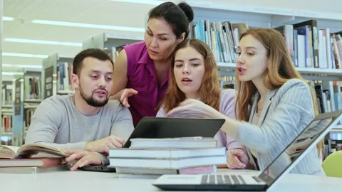 Friendly group of students is preparing for classes on a laptop, studying in the Stock Footage 326309813