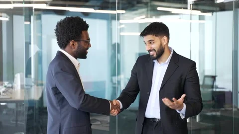 Friendly handshake between two businessmen standing and talking in bright glass  Stock Footage 336556491