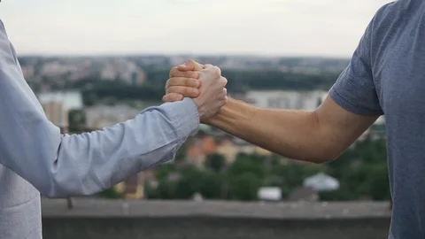 A friendly handshake of two men after meeting outdoors on a sunny day close-up Stock Footage 128963385