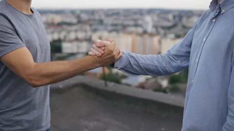 Friendly handshake of two men on the background of the city on a sunny day Stock Footage 128963337