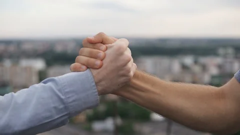 Friendly handshake of two men on the background of the city on a sunny day Stock Footage 129184664