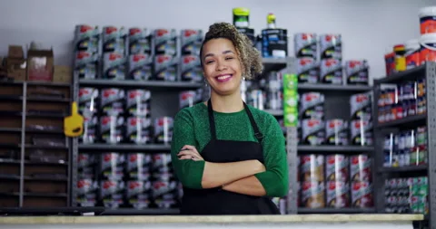 Friendly hardware store employee standing behind a counter, arms crossed, smilin Stock Footage 318744351