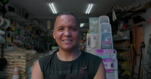 Friendly Hispanic man smiling at camera inside small hardware store, confident p Video stock 327385545