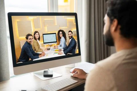 Friendly intelligent male freelancer using computer for work online sitting at Stock Photos