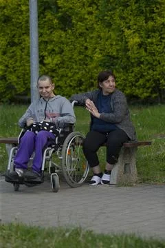 Friendly interaction between individual in wheelchair and companion outdoors Stock Photos