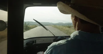 Friendly local driver with sombrero driving through vast desert landscape Stock Footage 86101937