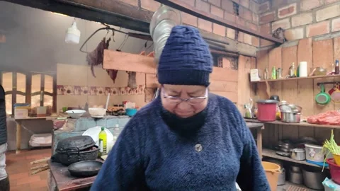Friendly local woman smiling in a rustic cozy kitchen preparing traditional Stock Footage 335920505