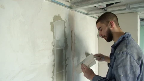 Friendly male builder spreading plaster on wall Stock-Footage 154451465