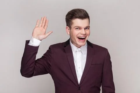 Friendly man keeps hand raise smiles sincerely expresses positive emotions. Stock Photos