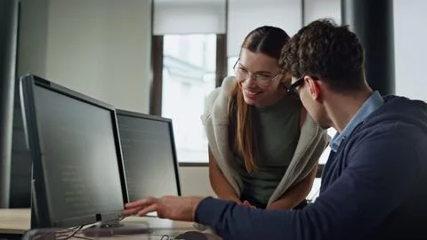 Friendly managers looking computer in office. It man coaching discussing code Stock Photos