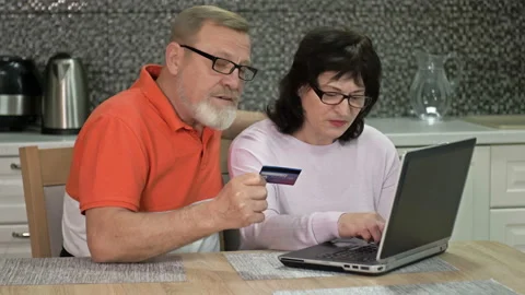 Friendly married couple using laptop at home for online shopping. Shopping Stock Footage 147661495