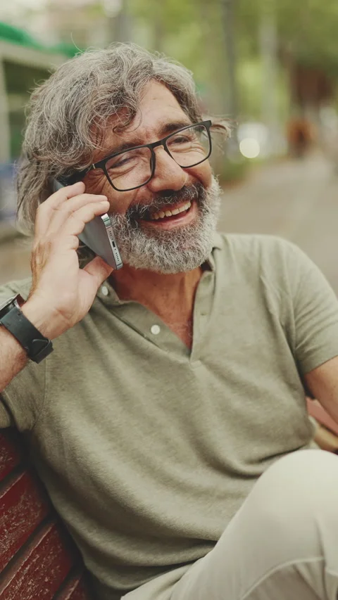 Friendly middle-aged man with gray hair and beard wearing casual clothes sits on Stock Footage 227021447