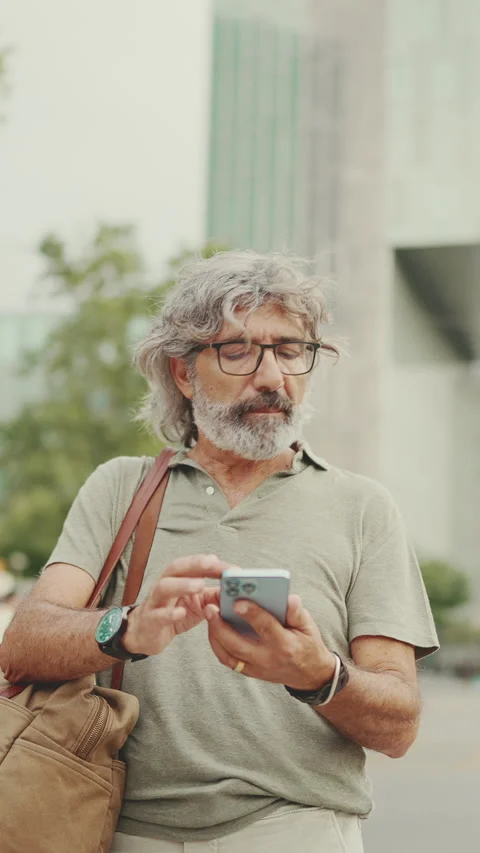 Friendly middle aged man with gray hair and beard looking at map trying to find Stock Footage 227022086