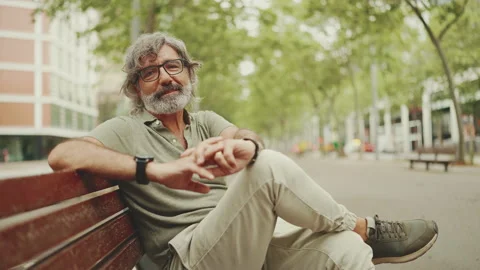Friendly middle-aged man with gray hair and beard wearing casual clothes sits on Stock Footage 227032008