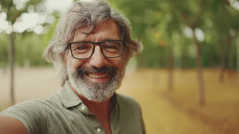 Friendly middle-aged man with gray hair and beard wearing casual clothes uses Stock Footage 227035040