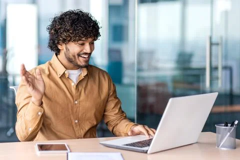 Friendly middle eastern programmer waving hand while using portable computer for 스톡 사진