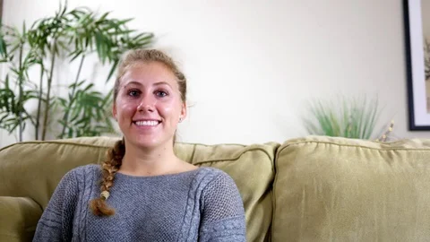 Friendly millennial blonde smiles at camera in modern living room Stock Footage 82763783