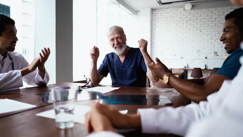 Friendly multi-ethnic team of doctors congratulate happy mature male physician Stock Footage 138360297