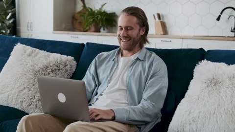 Friendly online conversation. A man is sitting on a couch in his living room Stock Footage 198344691