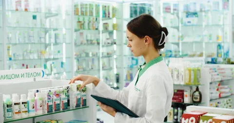 Friendly pharmacist does an inventory at a provided and modern pharmacy Stock Footage 220939364