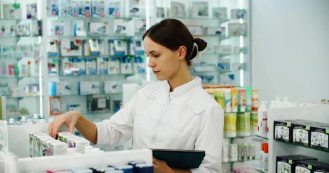 Friendly pharmacist does an inventory at a provided and modern pharmacy Stock Footage 220939503