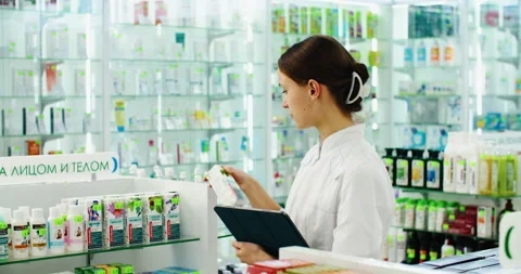 Friendly pharmacist does an inventory at a provided and modern pharmacy Stock Footage 221142565