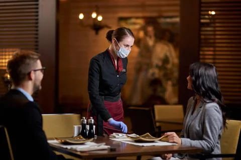 Friendly restaurant staff using mask and gloves for protection Stock Photos