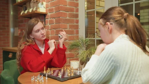 Friendly rivalry unfolds over strategic chess game in warm ambiance. Two women Stock Footage 345173485