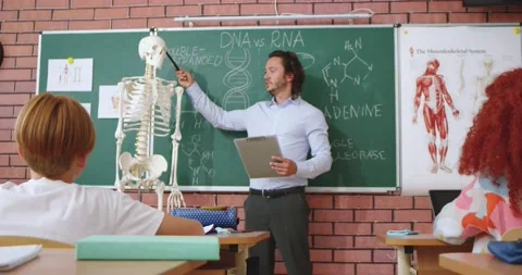 Friendly schoolmaster with clipboard in hands explaining structure of human body Stock Footage 201427204